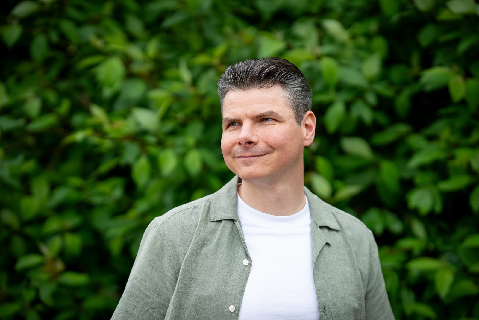 Mark kijkt zijdelings weg tegen een groene achtergrond